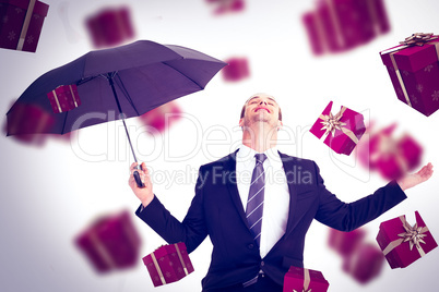 Composite image of businessman sheltering under black umbrella t