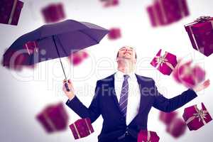 Composite image of businessman sheltering under black umbrella t