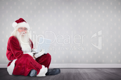 Composite image of santa sits and uses a laptop