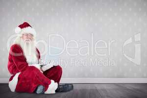 Composite image of santa sits and uses a laptop