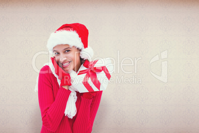 Composite image of festive brunette holding gift