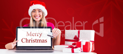 Composite image of festive blonde shopping online with laptop