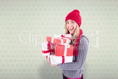 Composite image of festive blonde holding pile of gifts