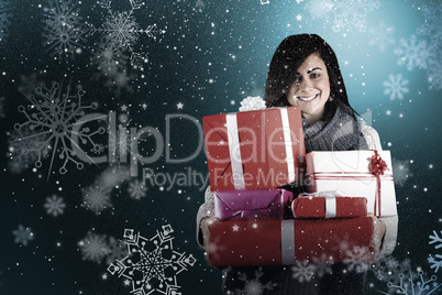 Composite image of smiling brunette holding many gifts