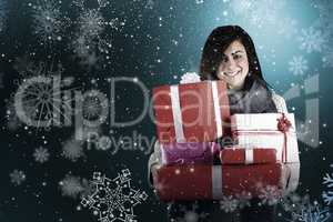 Composite image of smiling brunette holding many gifts