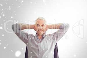 Composite image of relaxed mature businessman with hands behind