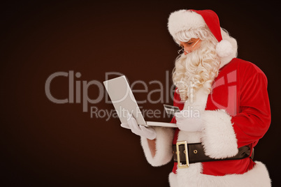 Composite image of santa claus shopping online with laptop Composite image of santa claus shopping online with laptop