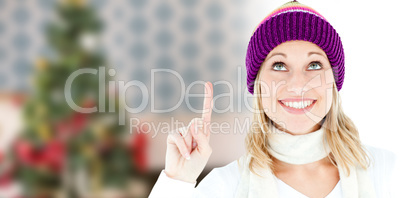 Composite image of bright woman with a colorful hat pointing upw