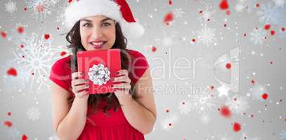 Composite image of festive brunette holding gift with bow