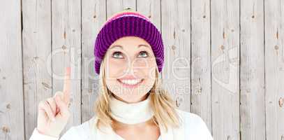Composite image of bright woman with a colorful hat pointing upw