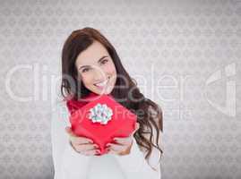 Composite image of happy brunette showing red gift with a bow
