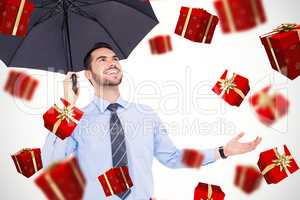 Composite image of happy businessman sheltering with a black umb