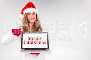 Composite image of festive blonde pointing to laptop