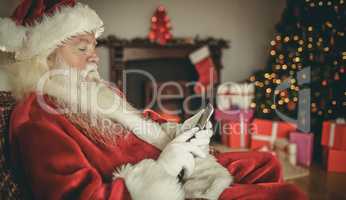 Concentrated santa using smartphone at christmas