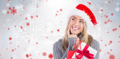 Composite image of festive blonde holding christmas gift and bag