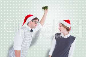 Composite image of geeky hipster holding mistletoe