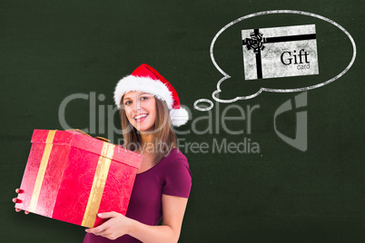 Composite image of young woman in santa hat holding gift box