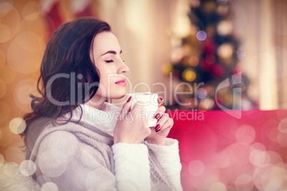 Composite image of brunette enjoying a hot chocolate at christma
