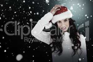 Composite image of confused brunette in santa hat