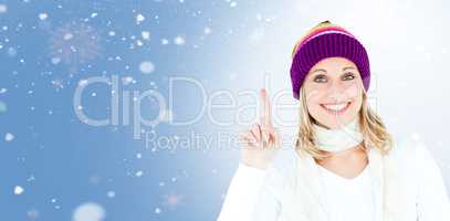 Composite image of joyful woman with a colorful hat pointing upw