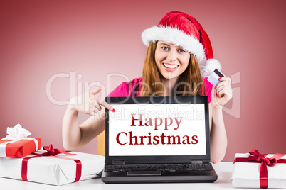 Composite image of festive redhead shopping online with laptop