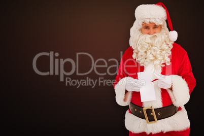 Composite image of happy santa holding paper and pen