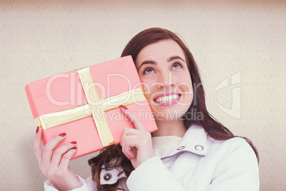 Composite image of portrait of a happy brunette holding gift