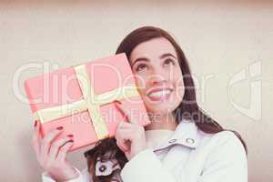 Composite image of portrait of a happy brunette holding gift