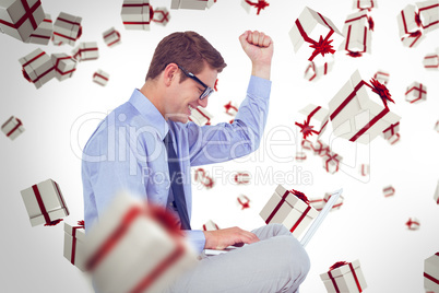 Composite image of businessman wearing glasses and using laptop