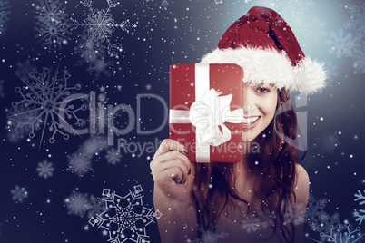 Composite image of festive redhead holding a gift