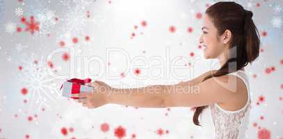 Composite image of festive brunette offering a gift