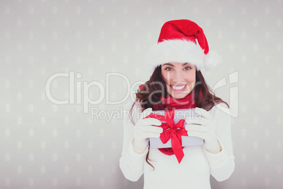 Composite image of festive brunette in santa hat holding gift