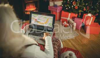 Santa sitting on the armchair and typing on laptop
