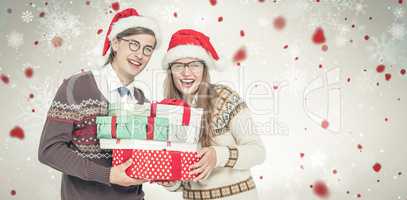Composite image of portrait of smiling man and woman wearing santa hats and holding gifts