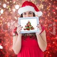 Composite image of festive brunette showing a tablet