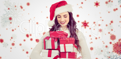 Composite image of festive brunette holding pile of gifts