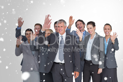 Composite image of smiling business team waving at camera