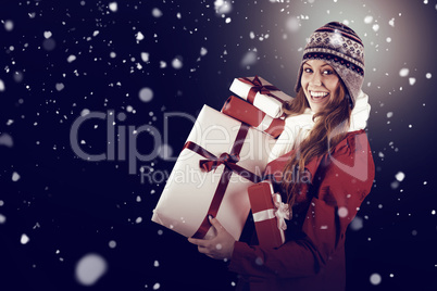 Composite image of pretty redhead in warm clothing holding gifts