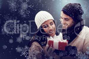 Composite image of winter couple holding gift