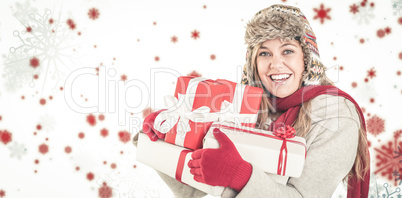 Composite image of happy blonde in winter clothes holding gifts