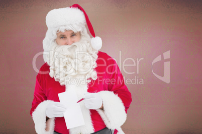 Composite image of happy santa holding paper and pen