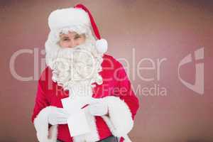 Composite image of happy santa holding paper and pen