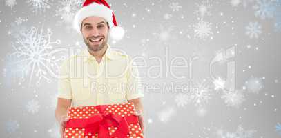 Composite image of smiling man wearing santa hat while holding g