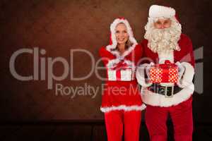 Composite image of santa and mrs claus smiling at camera offerin