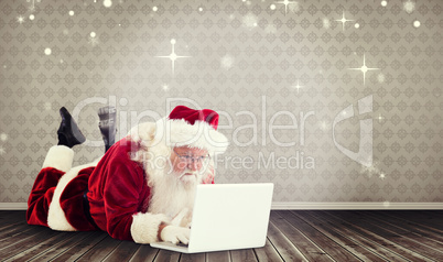 Composite image of santa lies in front of his laptop Composite image of santa lies in front of his laptop