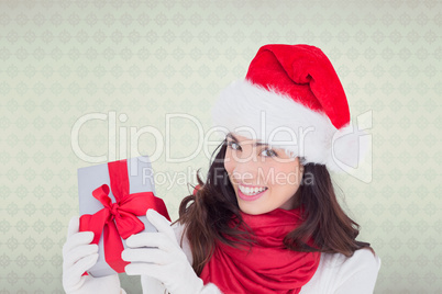 Composite image of excited brunette in santa hat showing gift
