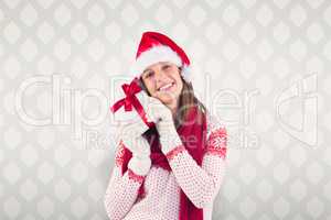 Composite image of attractive woman wearing santa hat with gift