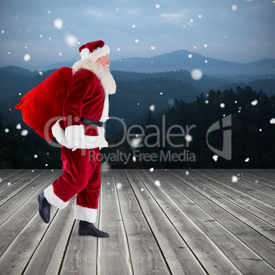 Composite image of santa carrying sack of gifts