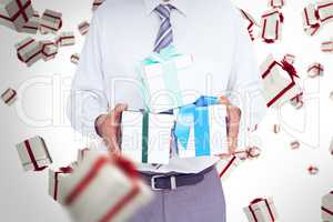 Composite image of businessman holding gifts