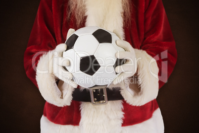 Composite image of santa holds a classic football